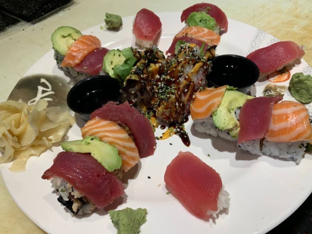 Sushi plated with salmon, tuna, avocado, and sauces